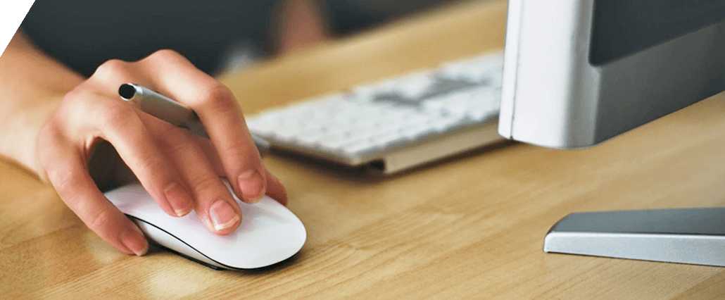 image of hand on computer mouse at desk with keyboard and monitor